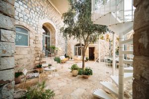 eine Terrasse mit weißen Stühlen und einem Backsteingebäude in der Unterkunft Azamra Inn Tzfat in Safed