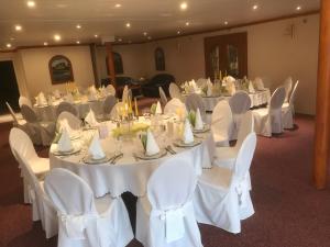 un salón de banquetes con mesas blancas y sillas blancas en Hotel Hohenzollern, en Schleswig