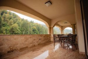 Un balcón con mesa y sillas y una gran ventana. en Casa Măiereană, en Anieş