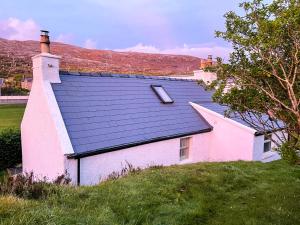 a white house with a black roof on a hill at Old Pier Cottage Tarbert in Tarbert