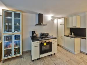 een keuken met witte kasten en een fornuis met oven bij Appartement Eifelsteig in Hollerath