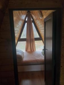 a window in a cabin with a bed in front of it at Popasul Dacilor in Predeluţ