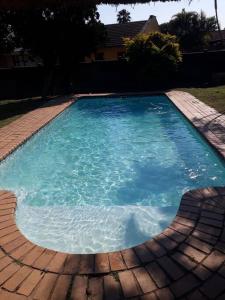 een groot zwembad van blauw water in een tuin bij Elegant 1-Bedroom Apartment with pool. in Richards Bay