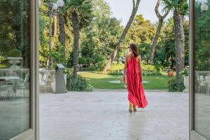 Una donna con un vestito rosso che cammina in un parco di Grand Hotel Rimini a Rimini