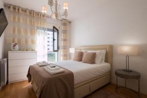a white bedroom with a bed and a window at Flamingos - 81258AL in Lisbon