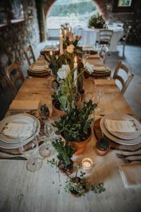 una larga mesa de madera con platos y flores. en Agriturismo Molino dei Frati en Trescore Balneario