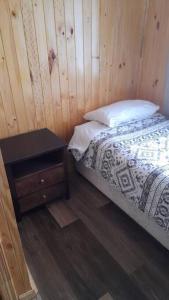sypialnia z łóżkiem i drewnianą ścianą w obiekcie Cabaña Volcán Hornopirén w mieście Hornopiren