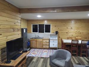 a kitchen with a television and a table with a chair at Cabaña Volcán Hornopirén in Hornopiren