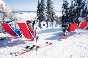 Un niño sentado en sillas en la nieve con esquís. en Break Sokos Hotel Koli, en Kolinkylä 99 fotos más