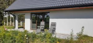 a white house with two chairs on a deck at zajęcza chata in Dolistowo