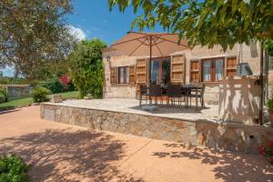 a house with an umbrella and a table and chairs at Alcudiola in Santa Margalida