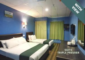 a hotel room with two beds and a tv at Sastria Hotel Sungai Petani in Sungai Petani