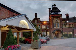 un edificio con una torre de reloj en un aparcamiento en Moor Hall Hotel, BW Premier Collection en Sutton Coldfield