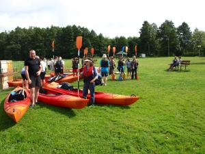 a group of people standing next to kayaks on a field at zajęcza chata in Dolistowo +17 photos