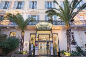 een gebouw met twee palmbomen ervoor bij Best Western Hotel Lakmi Nice in Nice