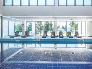 una piscina con una fila de sillas. en Novotel Geelong en Geelong