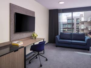 a living room filled with furniture and a tv at Novotel Geelong in Geelong
