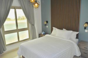 1 dormitorio con cama blanca y ventana en Amwaj Resort For Families Only, en Al Khobar