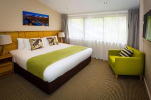 a bedroom with a large bed and a yellow chair at Club Wyndham Wanaka, Trademark Collection by Wyndham in Wanaka