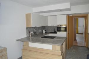 a kitchen with white cabinets and a gray counter top at Ferienwohnungen Restaurant Pizzeria Langreiter in Embach