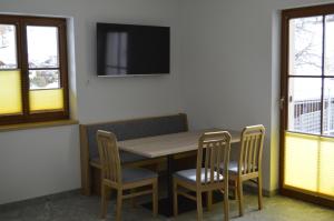 una sala da pranzo con tavolo, sedie e TV di Ferienwohnungen Restaurant Pizzeria Langreiter a Embach