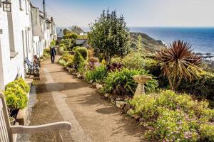 a man walking down a path next to the ocean at Cottage Sleeps 2- Parking Wood Fire Garden Pets in Lizard