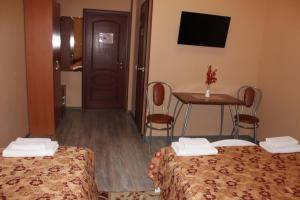 a hotel room with two beds and a table and a television at Hotel Dinastiya in Nizhny Novgorod