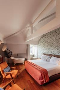 a bedroom with a large bed and a bath tub at Lisboa Carmo Hotel in Lisbon