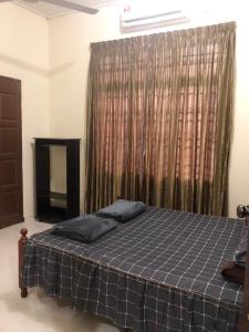a bed with two pillows in a room with a window at HOMESTAY SERI LAZUARDI 3 MACHANG ISLAMIC in Machang