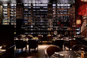 a restaurant with tables and chairs and a shelf of wine bottles at Conservatorium Hotel in Amsterdam