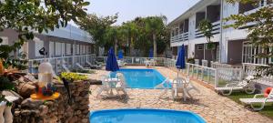 a hotel with a swimming pool with chairs and umbrellas at Hotel Pousada Ilha do Mar Bombinhas in Bombinhas