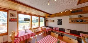 un restaurante con mesas y sillas rojas y blancas en Catrina Lodge, en Disentis