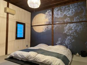 a bedroom with a bed with a painting on the wall at 元町の宿　雪月花 in Hakodate