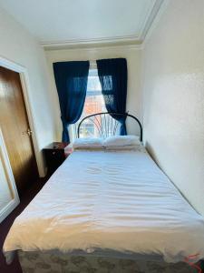 a bedroom with a bed with blue curtains and a window at The Roadhouse Hotel in Carlisle
