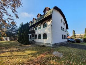 a large white building with a roof on a field at Nosztalgia Villa in Mezőkövesd