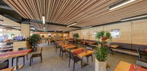 a restaurant with wooden tables and chairs and plants at Catrina Apartments in Disentis