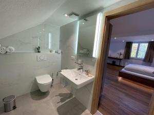 biała łazienka z toaletą i umywalką w obiekcie Hotel Reich am Ebnisee w mieście Kaisersbach