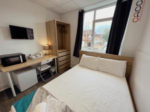a bedroom with a bed and a desk and a window at CACCO - Contractor Accommodation in Corby