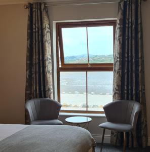 a bedroom with a window with two chairs and a table at Caisleain Oir Hotel in Annagry
