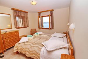 Schlafzimmer mit einem Bett, einer Kommode und einem Spiegel in der Unterkunft Holiday Home Katica in Vela Luka