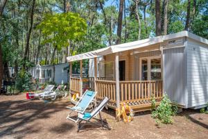 ein kleines Haus mit einer Veranda, Stühlen und Bäumen in der Unterkunft Flower Camping Les Biches in Saint-Hilaire-de-Riez