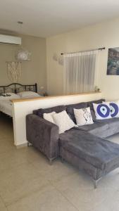 een woonkamer met een bank en een bed bij Rivkas zimmer in Ein Gedi