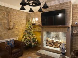 a living room with a christmas tree and a fireplace at The Captains Nook-Hot tub in Amble
