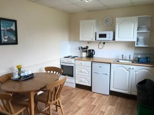 a kitchen with a table and chairs and a refrigerator at Wheal Rodney Holiday Park in Marazion