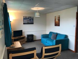 a living room with a blue couch and a tv at Wheal Rodney Holiday Park in Marazion