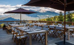 a restaurant with tables and umbrellas on a deck at Le Refuge de la Traye in Méribel