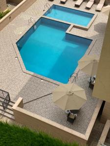 a swimming pool with two umbrellas and two chairs at Metro Apartments in Lagos