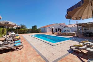 een zwembad met ligstoelen en een parasol bij Villa Oliva Al in Moncarapacho