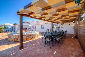 un patio con mesa y sillas bajo una pérgola en Villa Oliva Al en Moncarapacho