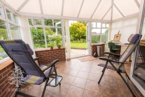 een serre met 2 schommelstoelen en een bureau bij The Monkey House B&B in Stone